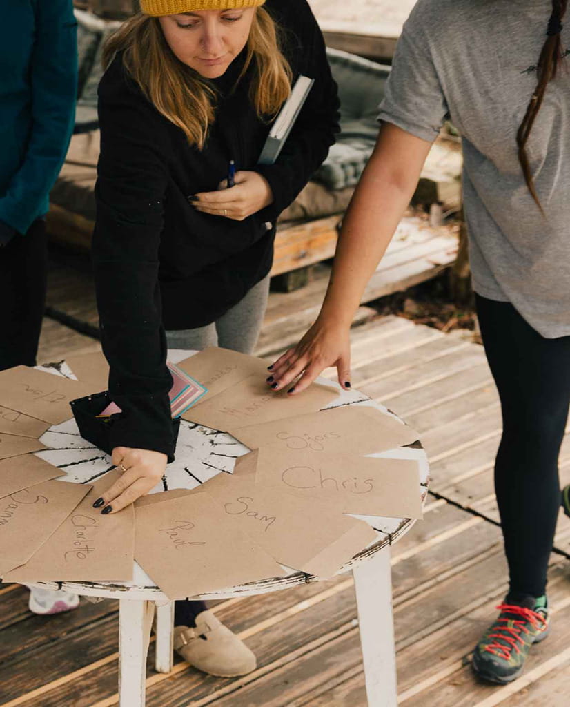 A group of people around a table reach for envelopes with hand written messages